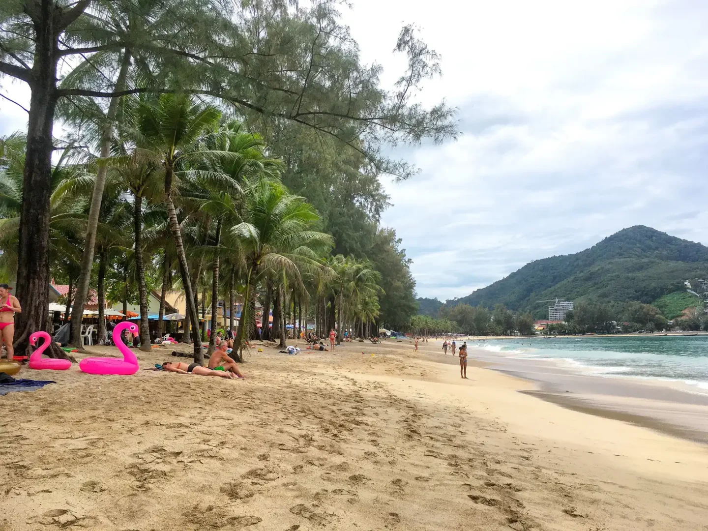 Kamala Beach in Phuket on a calm sunny day, with trees along the sand
